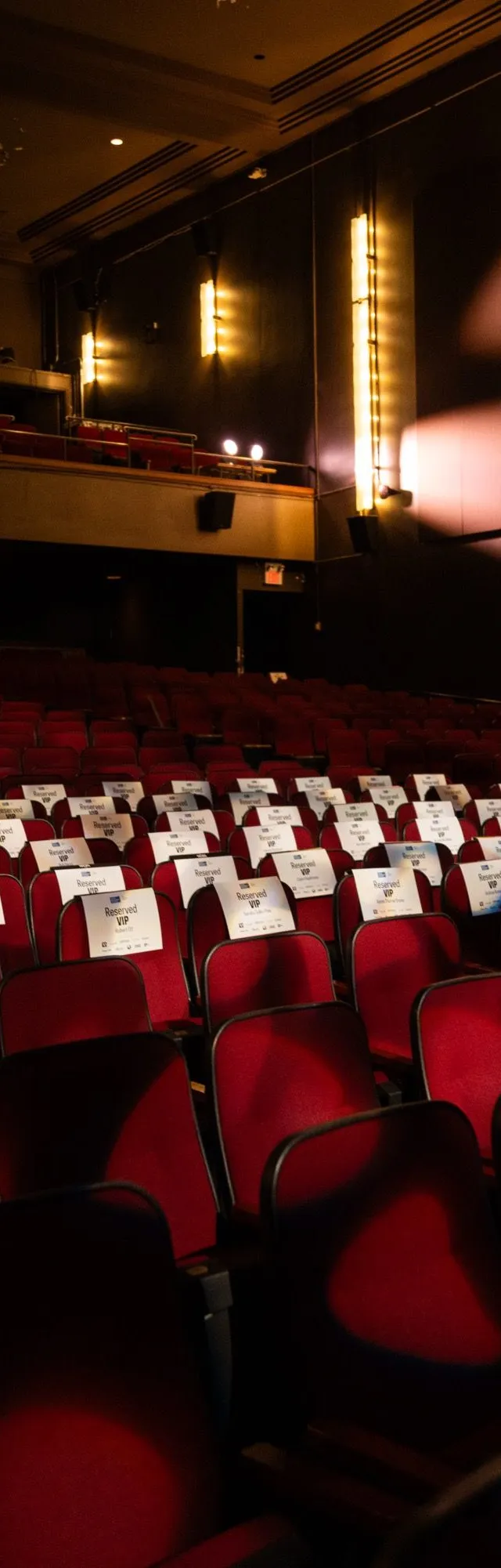 Rows of red theatre seats under warm wall sconces in the Chrysalis auditorium