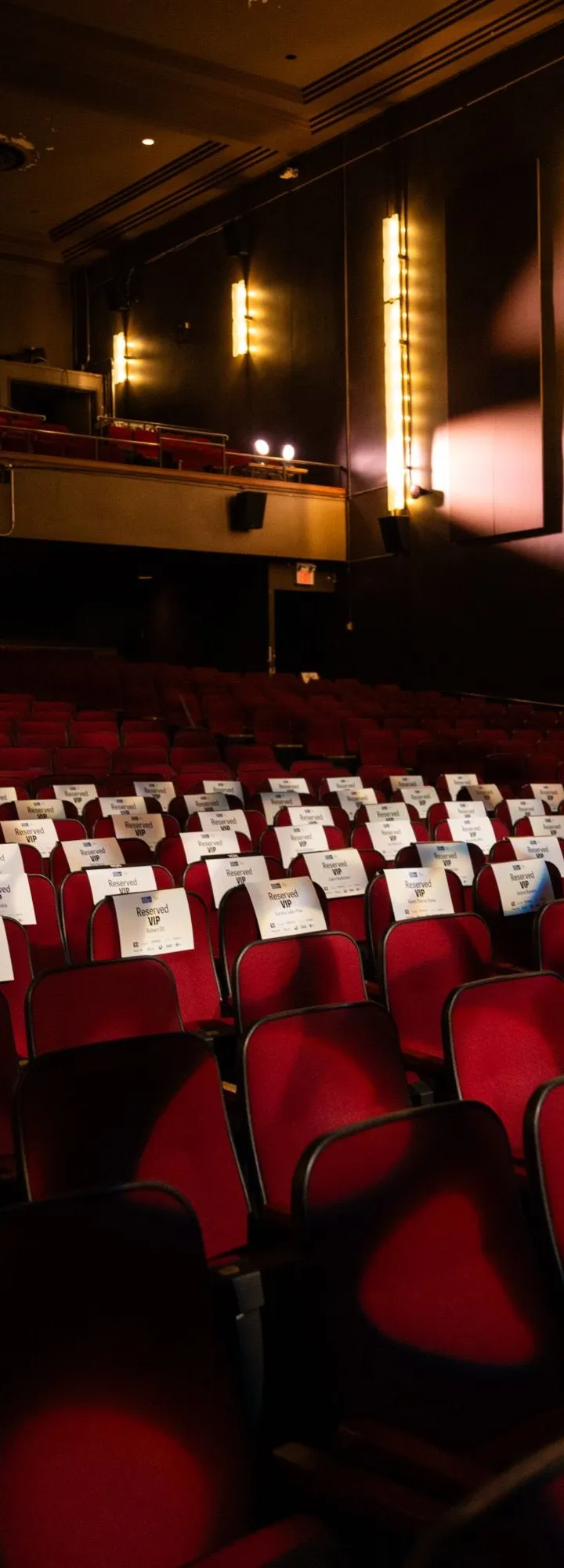 Rows of red theatre seats under warm wall sconces in the Chrysalis auditorium