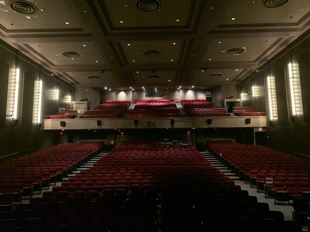 The empty Chrysalis auditorium — rows of red seats, a balcony, and a coffered ceiling seen from the stage