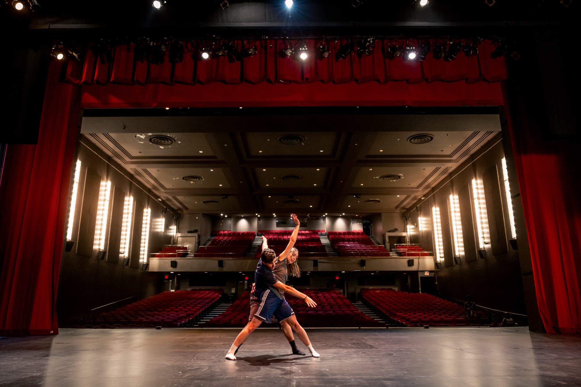 Two dancers working through a duet on the Chrysalis stage, the empty house behind them